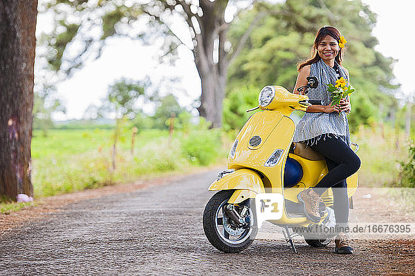 Vietnamesische Frau mit gelbem Motorroller in einer ländlichen Gegend in Vietnam