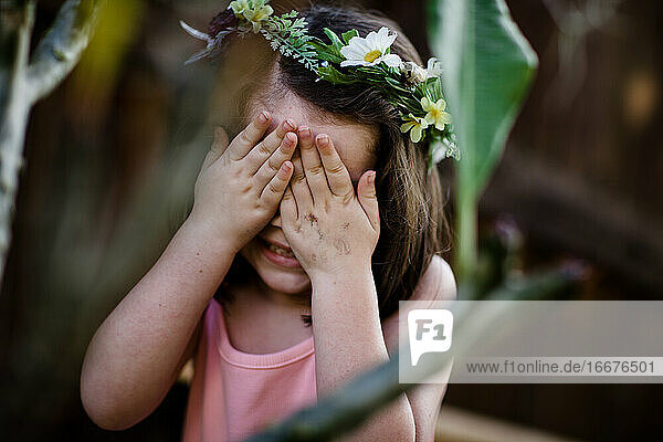 Junges Mädchen mit Blumenkrone  die die Augen verdeckt