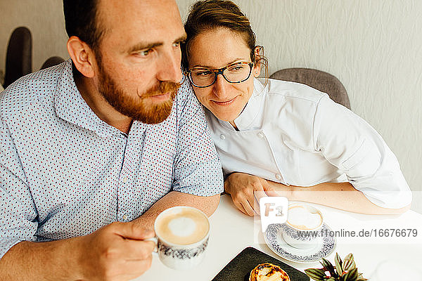 Paar trinkt Cappuccino und sitzt am Tisch in einem Cafe