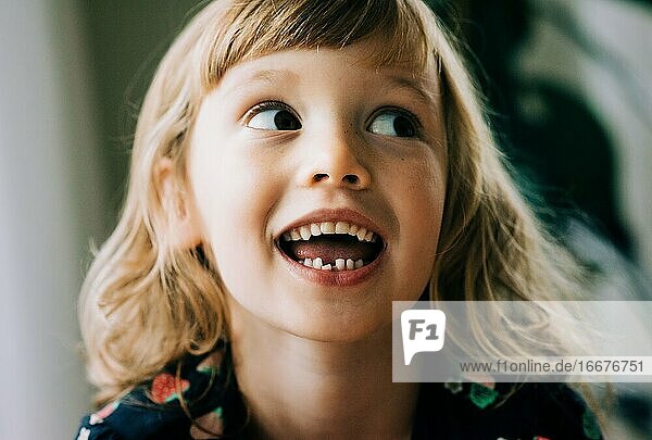 young girl smiling showing her wobbly tooth looking happy