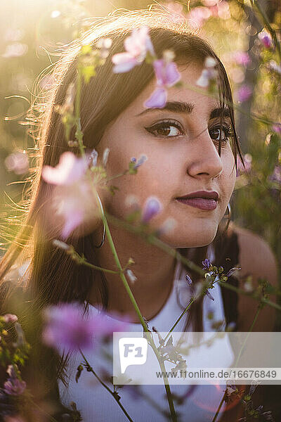 Porträt eines lächelnden Teenagers inmitten von Blumen in der Natur