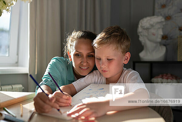 Konzentrierte Mutter und Sohn skizzieren im Planer