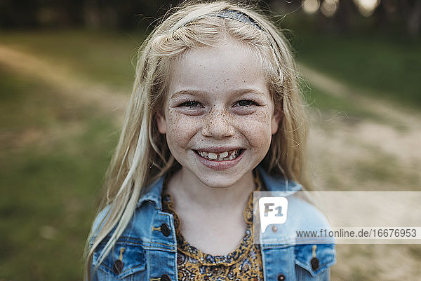Close up portrait of school aged girl smiling outside