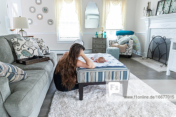 New mother in love playing with newborn baby in living room.