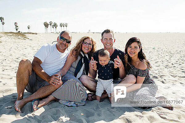 Family of Five Sitting on Beach Smiling for Camera