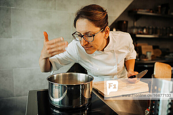 Female chef smelling hot food while cooking in restaurant kitchen