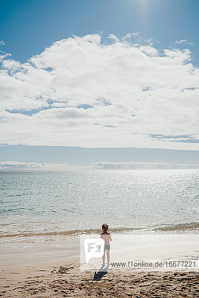 Junge  der an einem sonnigen Tag im Urlaub am Strand ins Wasser geht