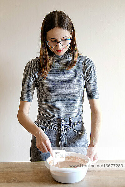 Frau in T-Shirt und Jeans bereitet in ihrer Küche hausgemachte Cupcakes zu