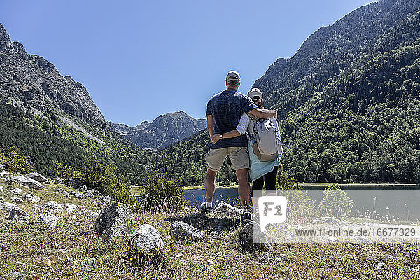 Touristisches Paar mittleren Alters  das sich in der Nähe eines Bergsees in den spanischen Pyrenäen umarmt See in den spanischen Pyrenäen