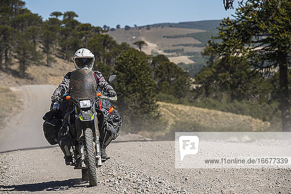 woman on touring motorbikes driving on gravel road in Argentina