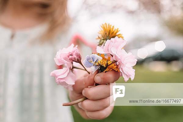 Kleinkind Mädchen hält einen kleinen Strauß von Wildblumen und Unkraut