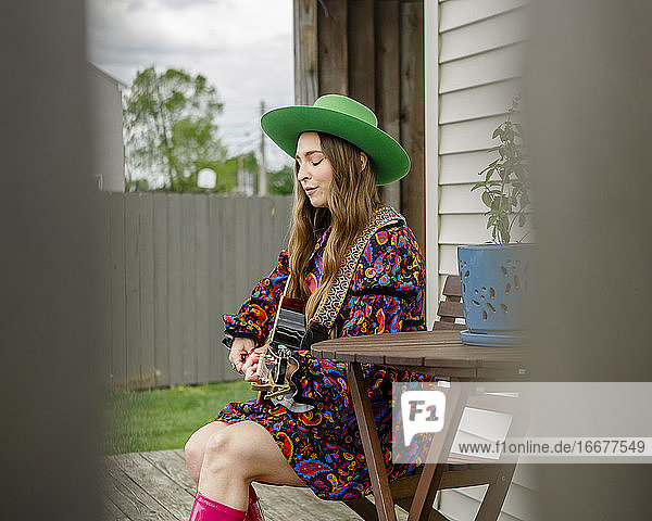 Seitenansicht einer Frau mit geschlossenen Augen  die auf einer Veranda sitzt und Gitarre spielt