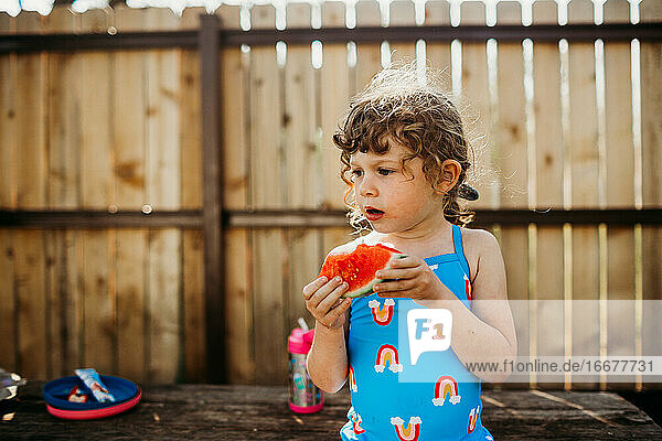 Nahaufnahme eines jungen Mädchens  das auf einem Picknicktisch sitzt und Wassermelone isst
