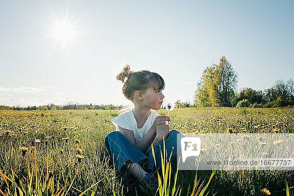 Ein junges Mädchen saß in einem friedlichen Blumenfeld im Sommer