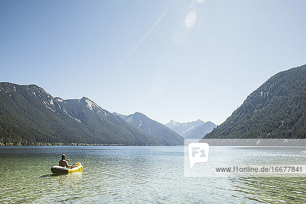 Rear view of man paddling inflatable boat on Chilliwack Lake.