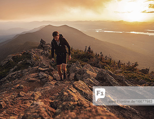 Male hiker walks along Appalachian Trail on Bigelow Mountain at sunset