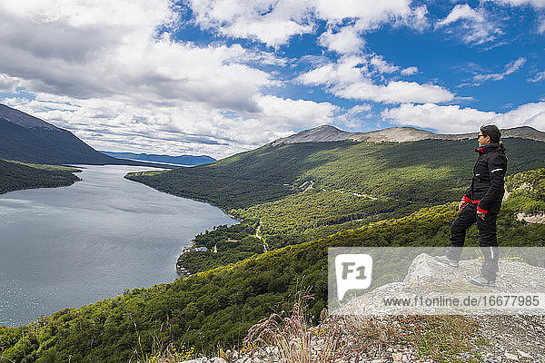 Woman in motorbike clothes is looking over lake in Tierra del Fuego