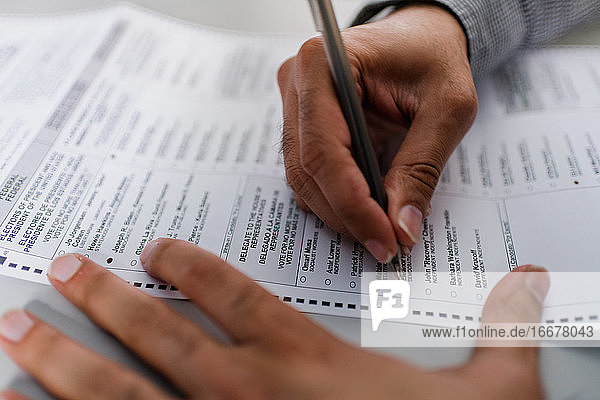 Nahaufnahme der Hände eines Mannes beim Ausfüllen des Wahlzettels für die Wahl