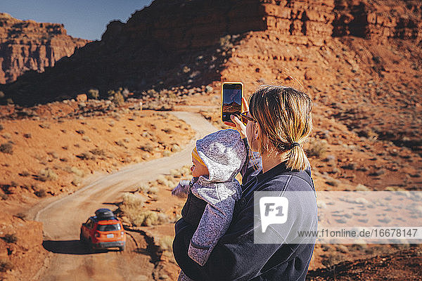 A woman with a child is taking pictures in Valley of the Gods  Utah