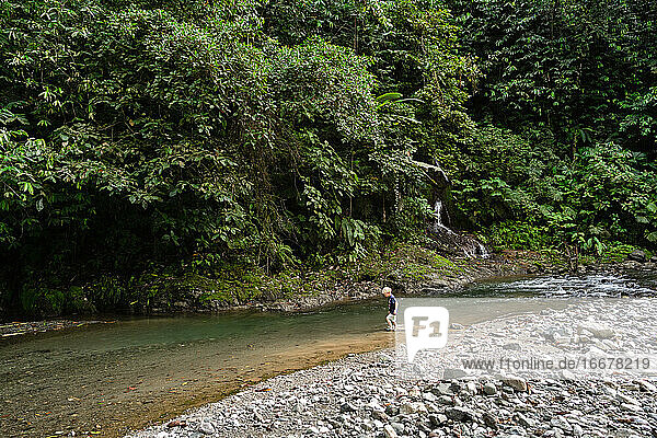 Child walking in river in rain forest of Costa Rica