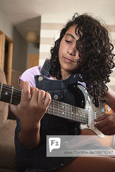 Nahaufnahme eines jungen Mädchens  das sich beim Spielen der E-Gitarre konzentriert