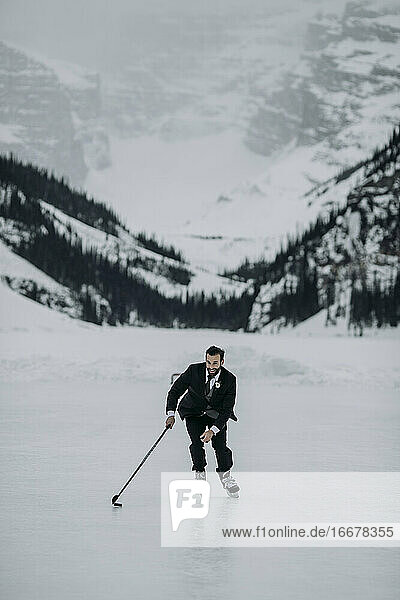 man in suit plays hockey on frozen Lake Louise  Alberta  Canada