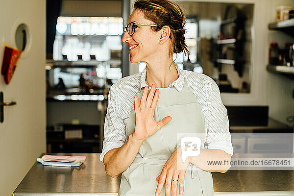 Weibliche Köchin macht Gesten  während sie in der Restaurantküche steht