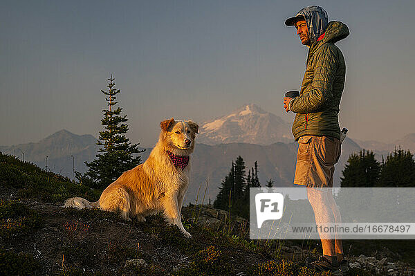 Hund und Wanderer bei Sonnenuntergang mit Vulkan in der Ferne