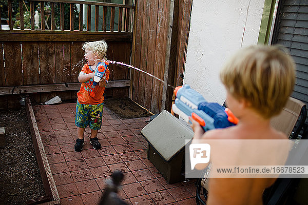 Brothers Playing with Water Guns in Front Yard