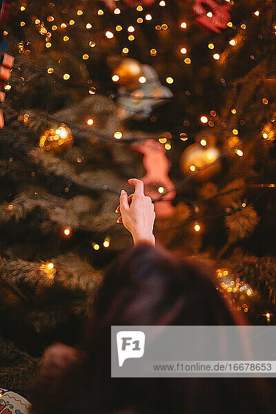 Rückansicht eines jugendlichen Mädchens  das sich unter dem Weihnachtsbaum etwas wünscht