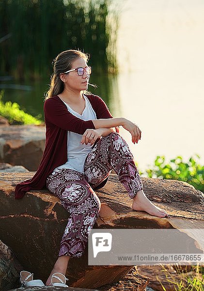 Eine Frau saß auf einem Felsen am Seeufer