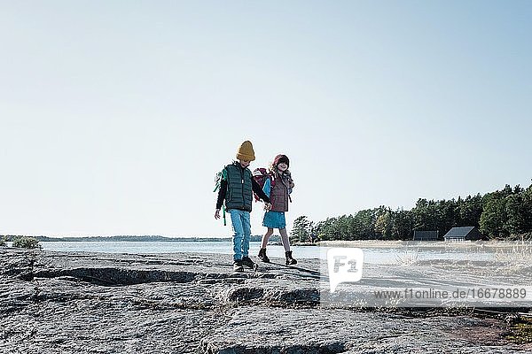 siblings hiking holding hands smiling by the ocean