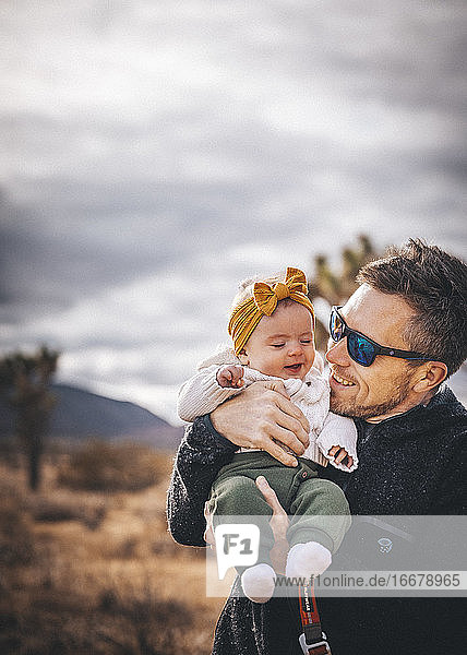 A man with a baby is standing in a desert of California