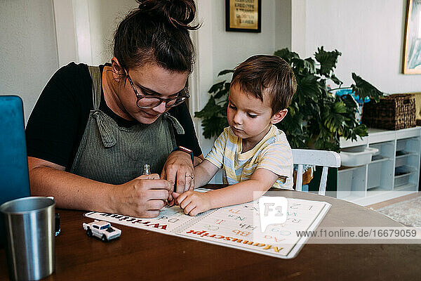 Mom and young son painting finger nails at kitchen table