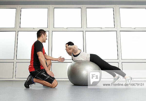 Personal Trainer hilft Kunden im Fitnessstudio im Vereinigten Königreich