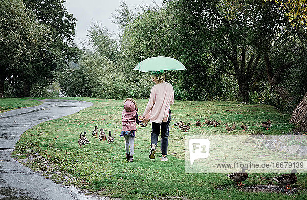 Mutter und Tochter gehen zusammen spazieren und halten sich an einem regnerischen Tag an den Händen