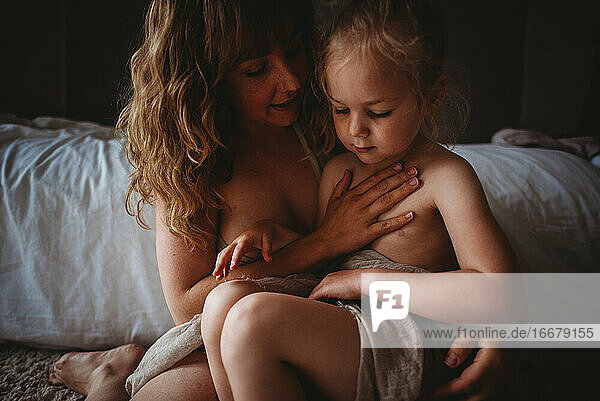 Mutter mit Hand auf der Brust der Tochter im Schlafzimmer zu Hause