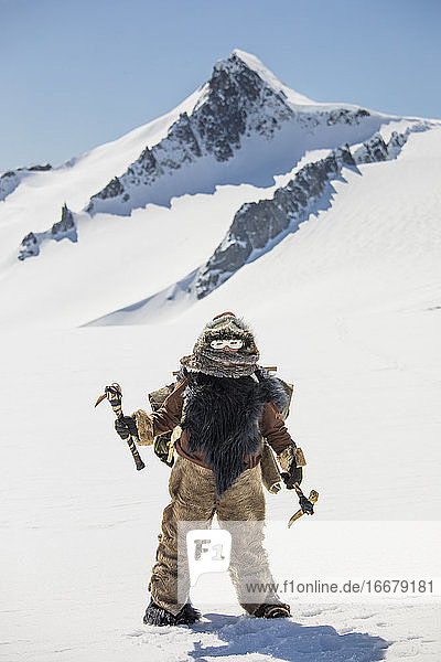 Jäger der Ureinwohner  der einen Pelz trägt und ein traditionelles Eispickelwerkzeug hält.