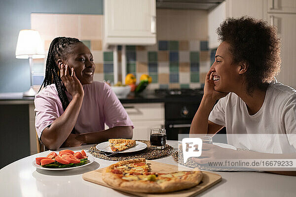 Happy diverse girlfriends eating pizza together