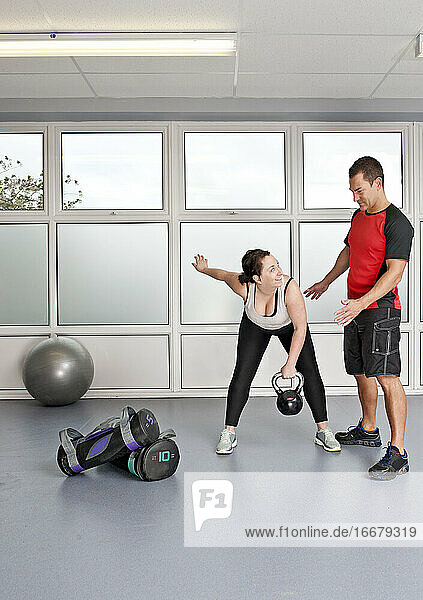 personal trainer helping client at gym in the UK