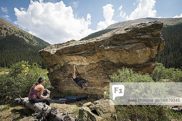 Frau schaut auf Freundin beim Bouldern am Fels