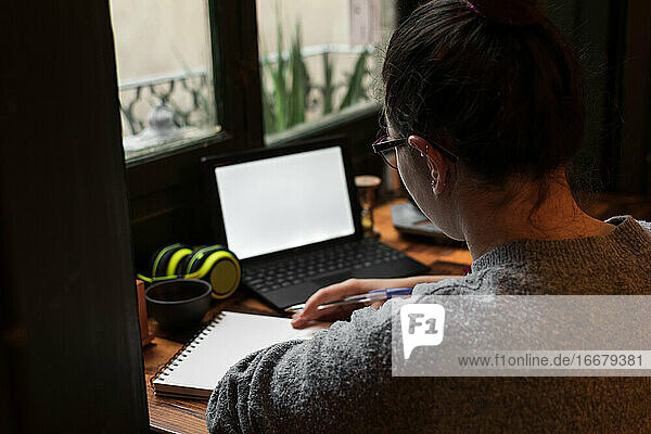 Ein junger Student arbeitet an einem Tisch in der Nähe eines Kneipenfensters. Nahaufnahme