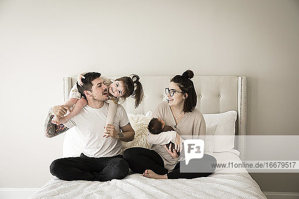 Happy Millennial Family Plays Together on Bed