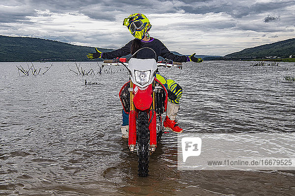 Frau posiert auf ihrem Dirt-Bike in einem See bei Pak Chong / Thailand