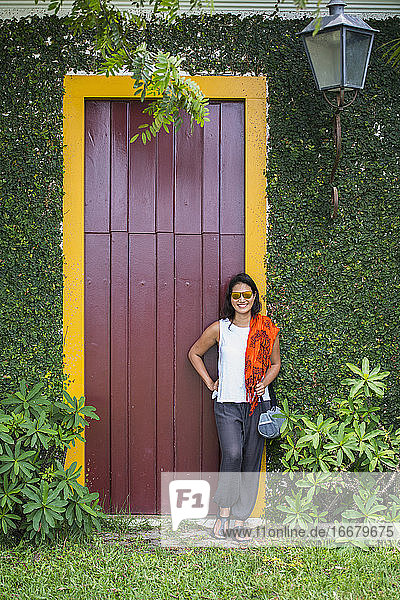 Frau posiert vor einer Tür mit gelbem Rahmen in Paraty / Brasilien