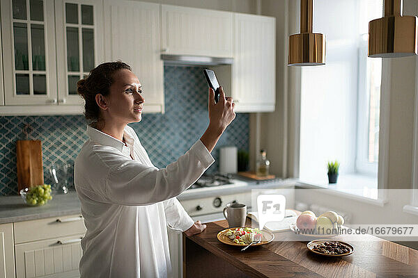 Geschäftsfrau nutzt Smartphone zur Kommunikation in der Küche