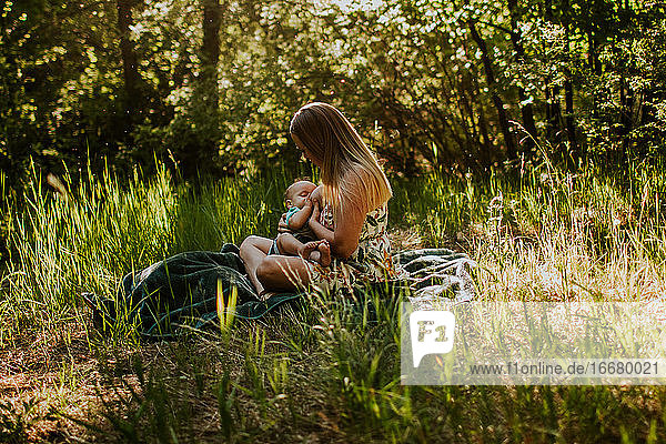 Mother sitting and nursing baby in tall grass