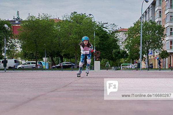 Mädchen auf der Straße skatet mit Inline-Skates und Helm