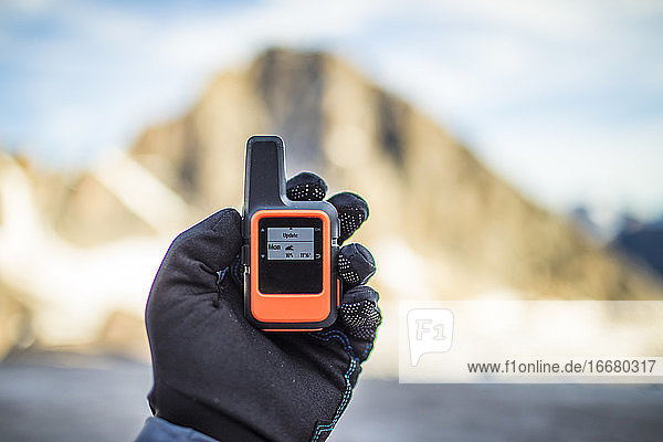 Bergsteiger prüft das Wetter über ein kleines Satellitenkommunikationsgerät.