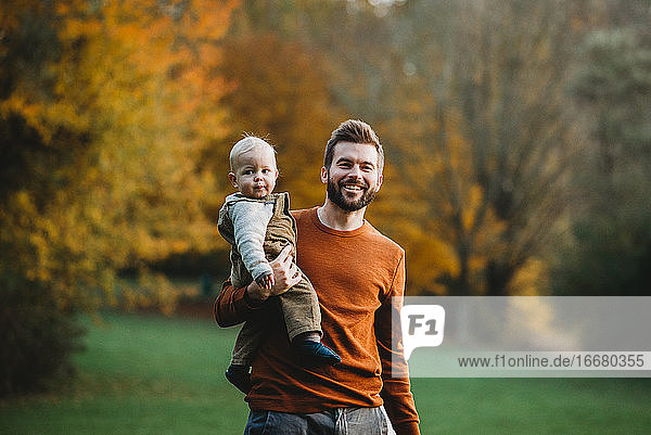 Father and son smiling at the park in a Fall day wearing earth tones